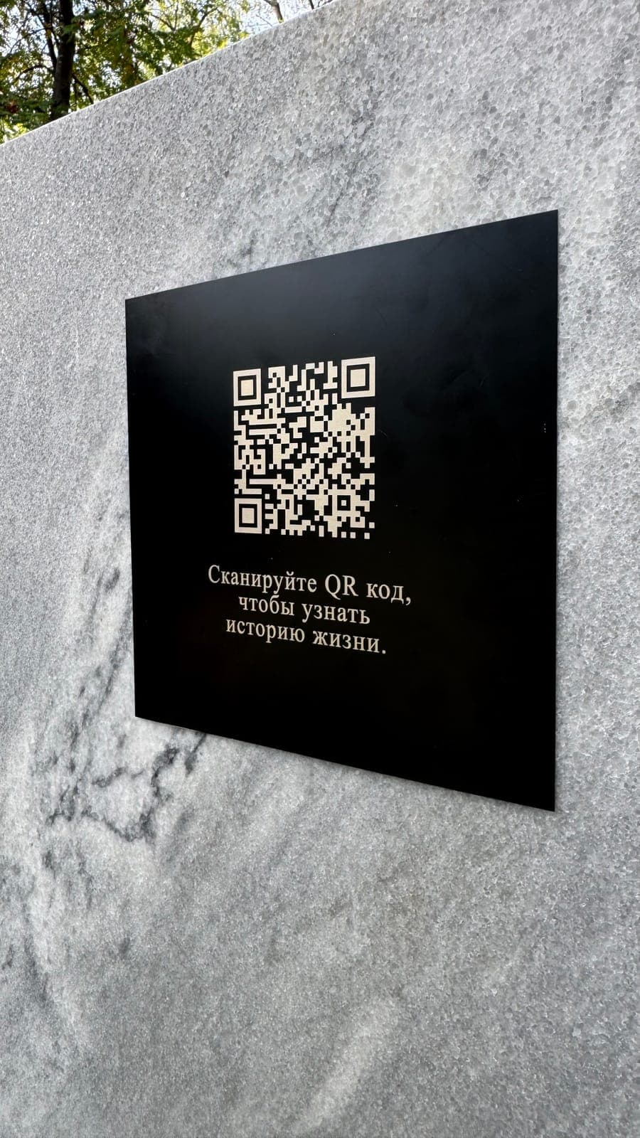 Чёрная алюминиевая табличка с QR‑кодом на светлом мраморе