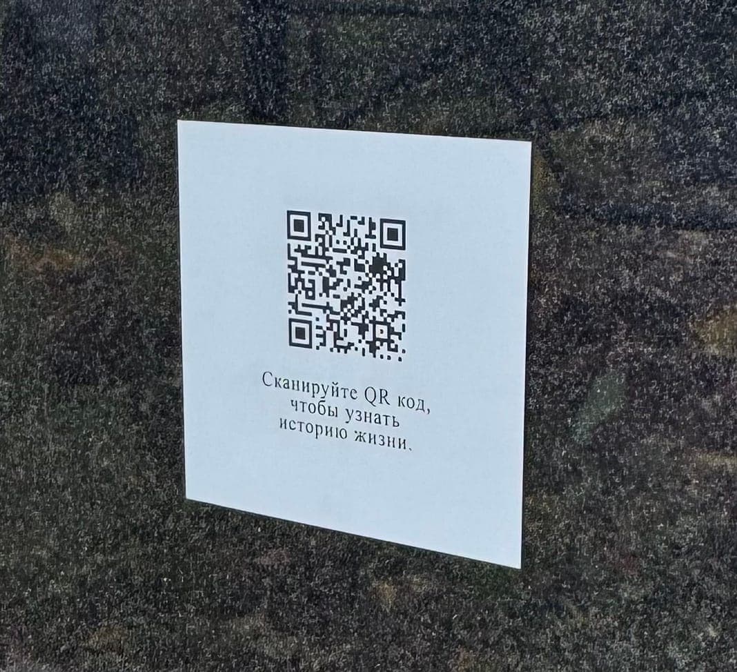Белая алюминиевая табличка с QR‑кодом на чёрном граните